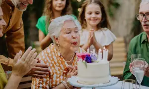 Babcia zdmuchuje świeczki na torcie, rodzina składa życzenia na 51 urodziny.