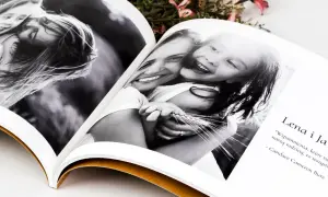 Otwarta fotoksiążka z czarno-białymi zdjęciami uśmiechniętej mamy i córki. Piękne fotoksiążka przykłady.