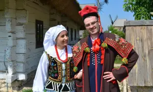 Para w tradycyjnych strojach krakowiak, gotowa do tańca. Ona w białej chustce i korale, on w czerwonej czapce z pawim piórem.