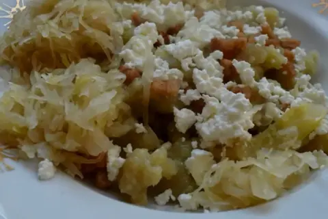 Szare kluchy z kapustą po poznańsku, posypane białym serem i skwarkami. Pyszne danie, które smakuje jak u babci.