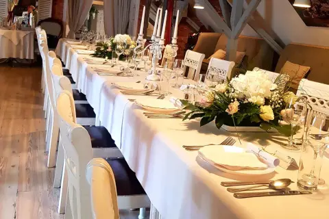 Elegancko nakryty stół w restauracji, gotowy na przyjęcie. Zastanawiasz się, ile trwają chrzciny w restauracji? Zazwyczaj to kilka godzin, w zależności od programu.