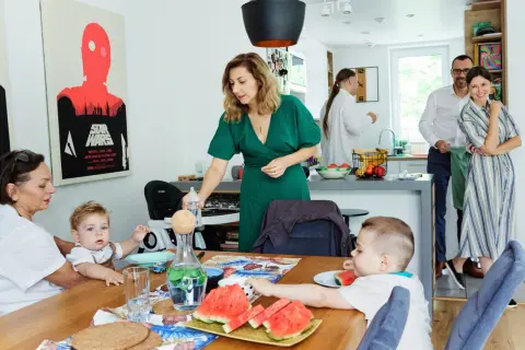 Rodzina przy stole, przygotowania do rodzinnego spotkania. Dzieci jedzą arbuzy, a dorośli rozmawiają. To piękne chrzest zdjęcia.