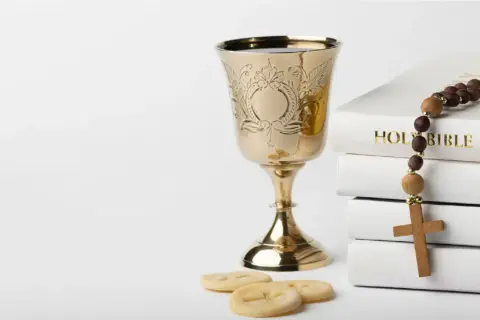 Złoty kielich, hostie, różaniec i Biblia. Symbolika sakramentu, który rozpoczyna życie w wierze, jak akt chrztu.